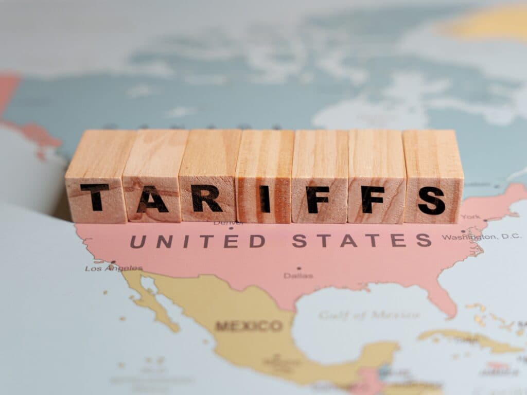 Wooden blocks spelling TARIFFS are placed on a map of North America