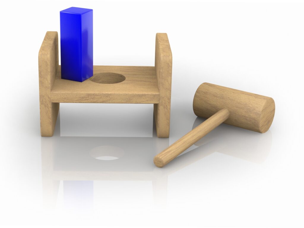 A child's toy showing a square peg over a round hole.